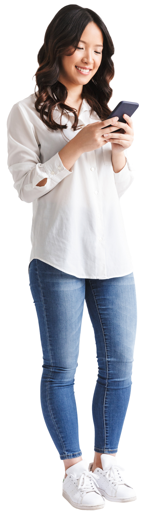 Une femme en jeans et chemise blanche utilise son téléphone portable.